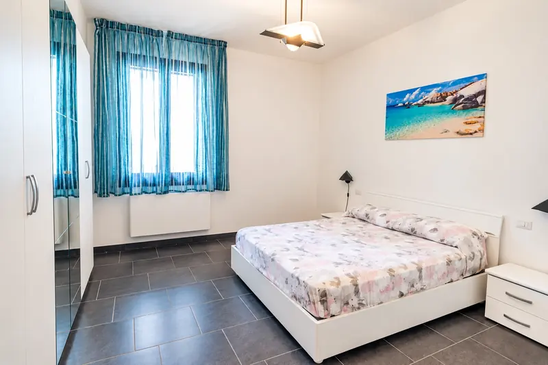 La camera matrimoniale con la finestra e il quadro del mare
