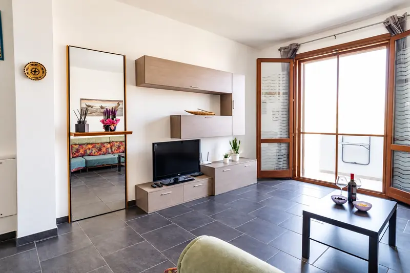 Il soggiorno con la TV, lo specchio e la porta-finestra