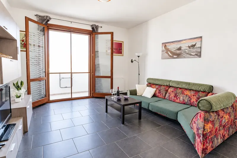 Il soggiorno con il divano e la porta-finestra aperta sul balcone