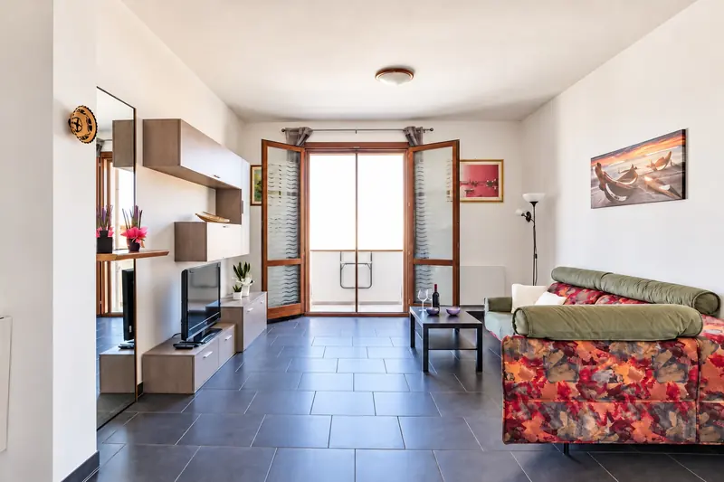 Il soggiorno visto dall'ingresso, con la porta-finestra sul balcone in fondo